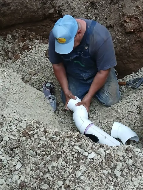 Joe Messina fitting a new PVC sewer line in an open trench